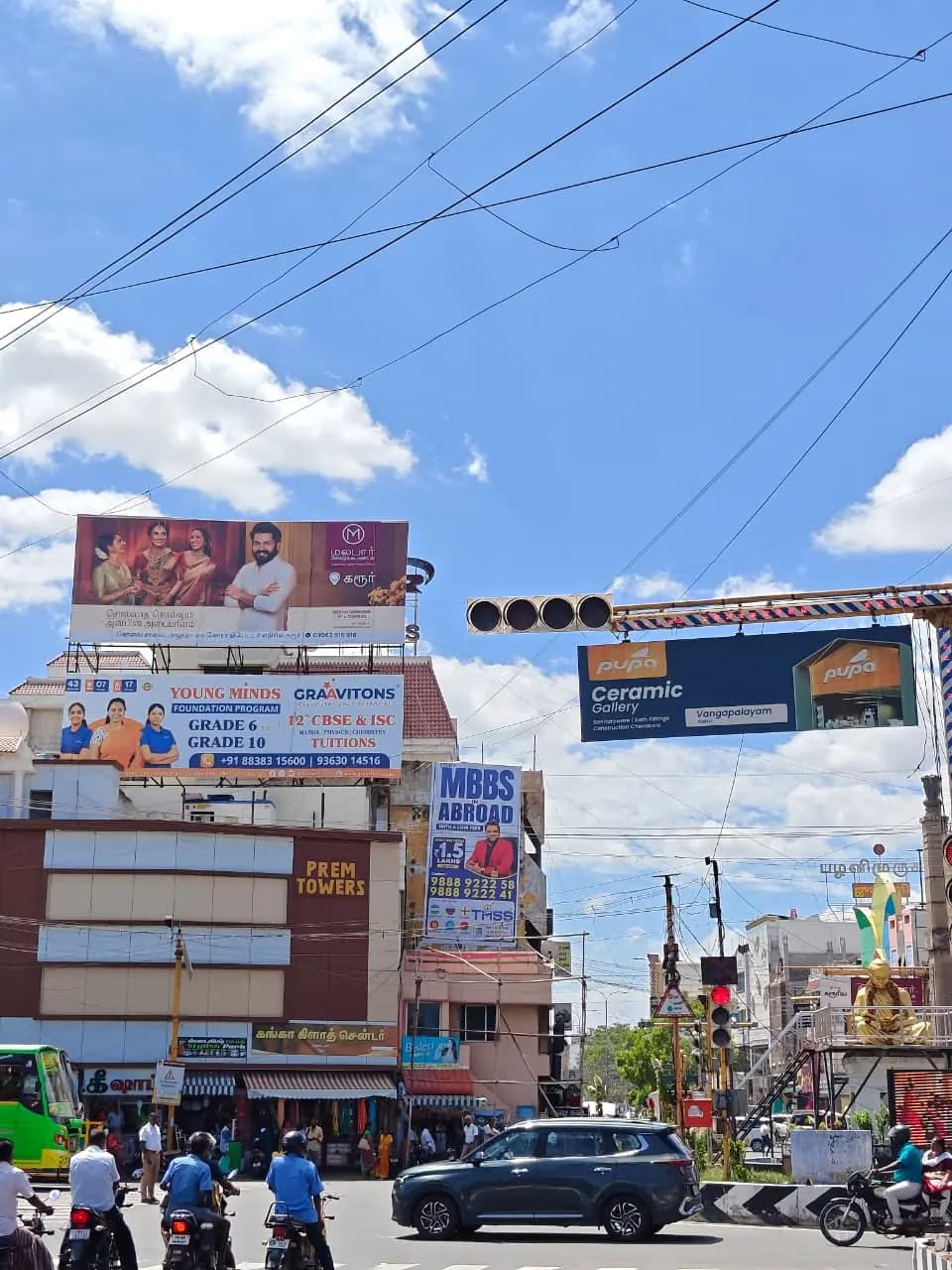 Stacked rooftop hoardings and signal gantry ads at junction