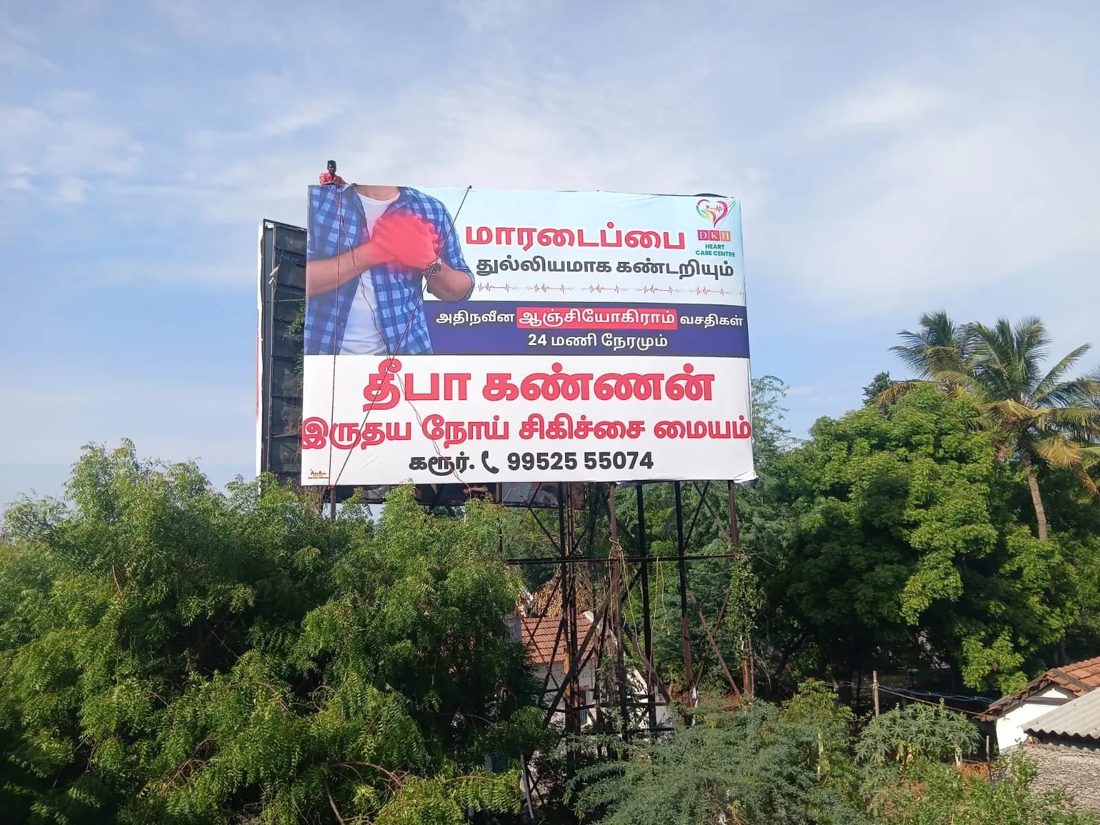 Tall roadside hoarding with Tamil copy against a blue sky
