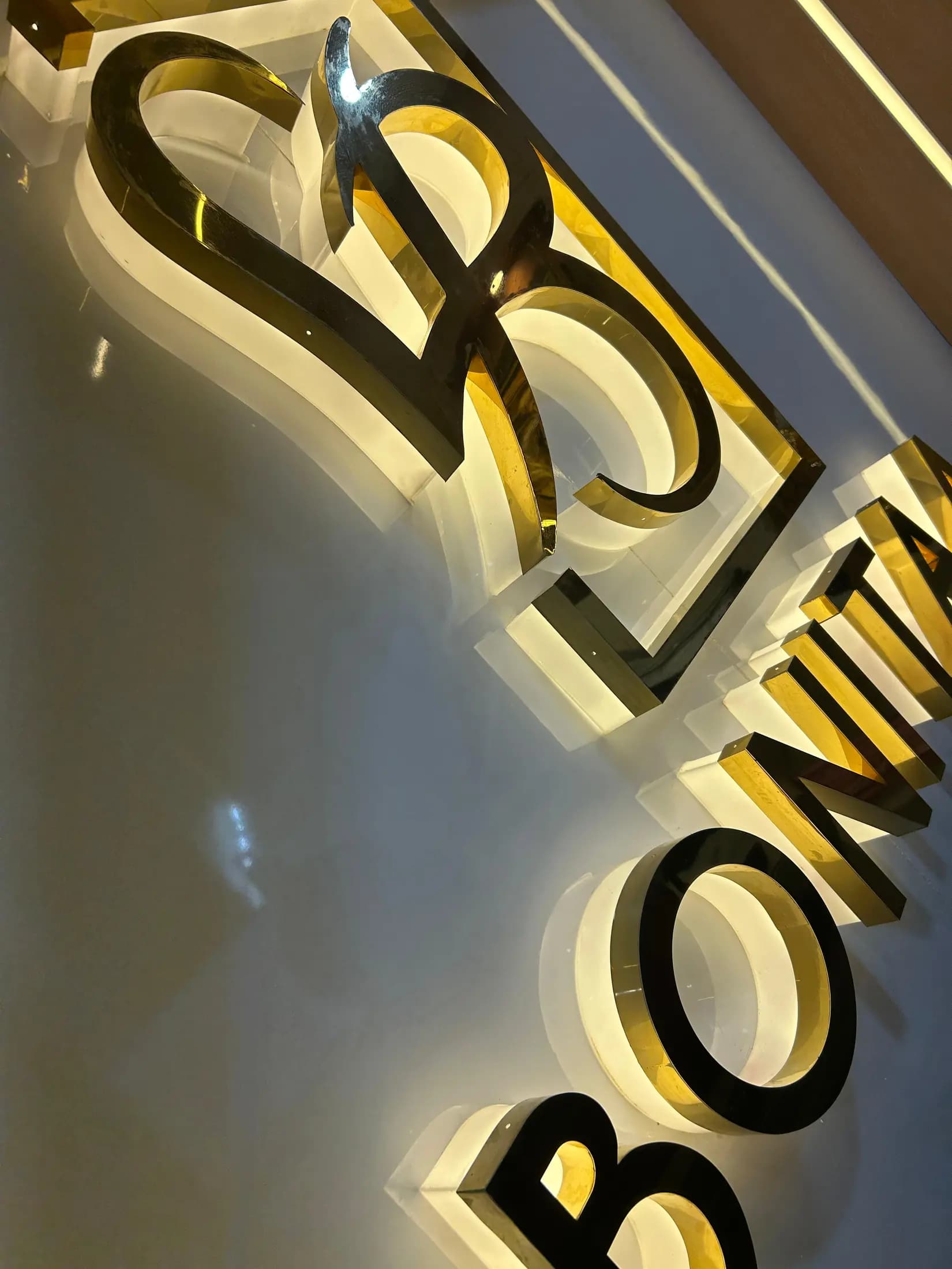 Close view of gold 3D letters glowing against a dark wall