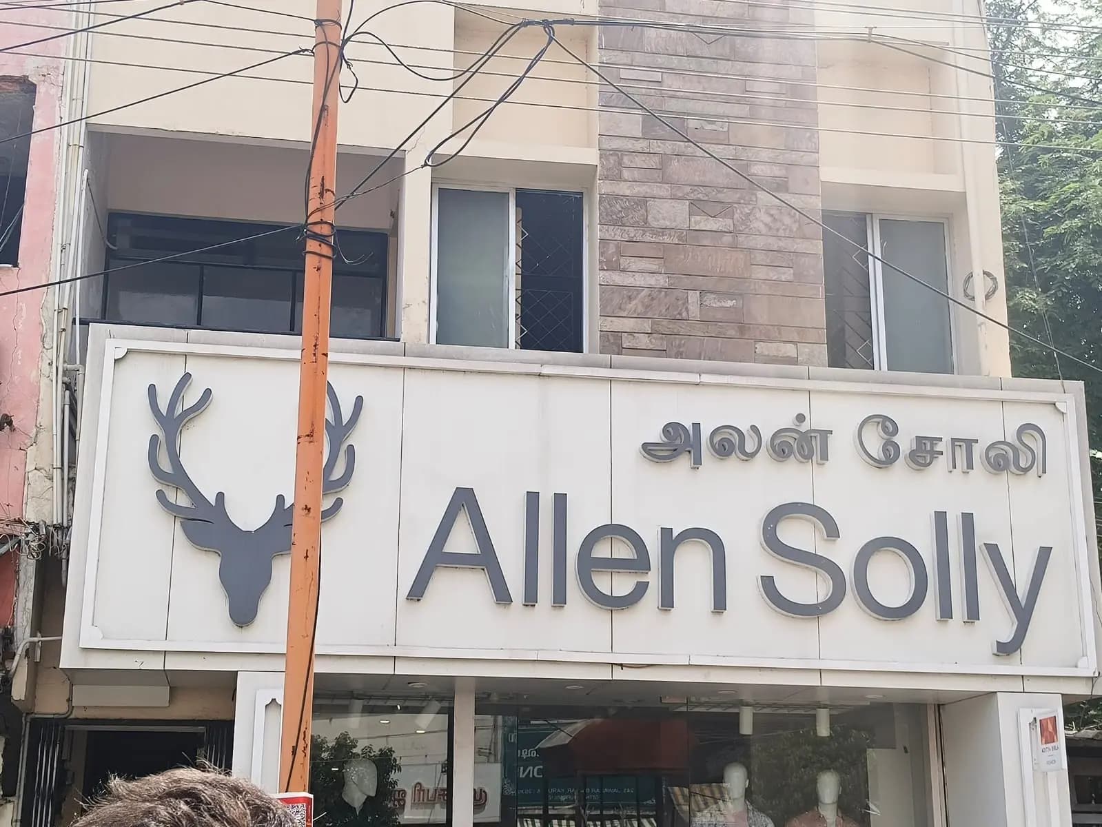 Large white fascia board with brand logo on a store front