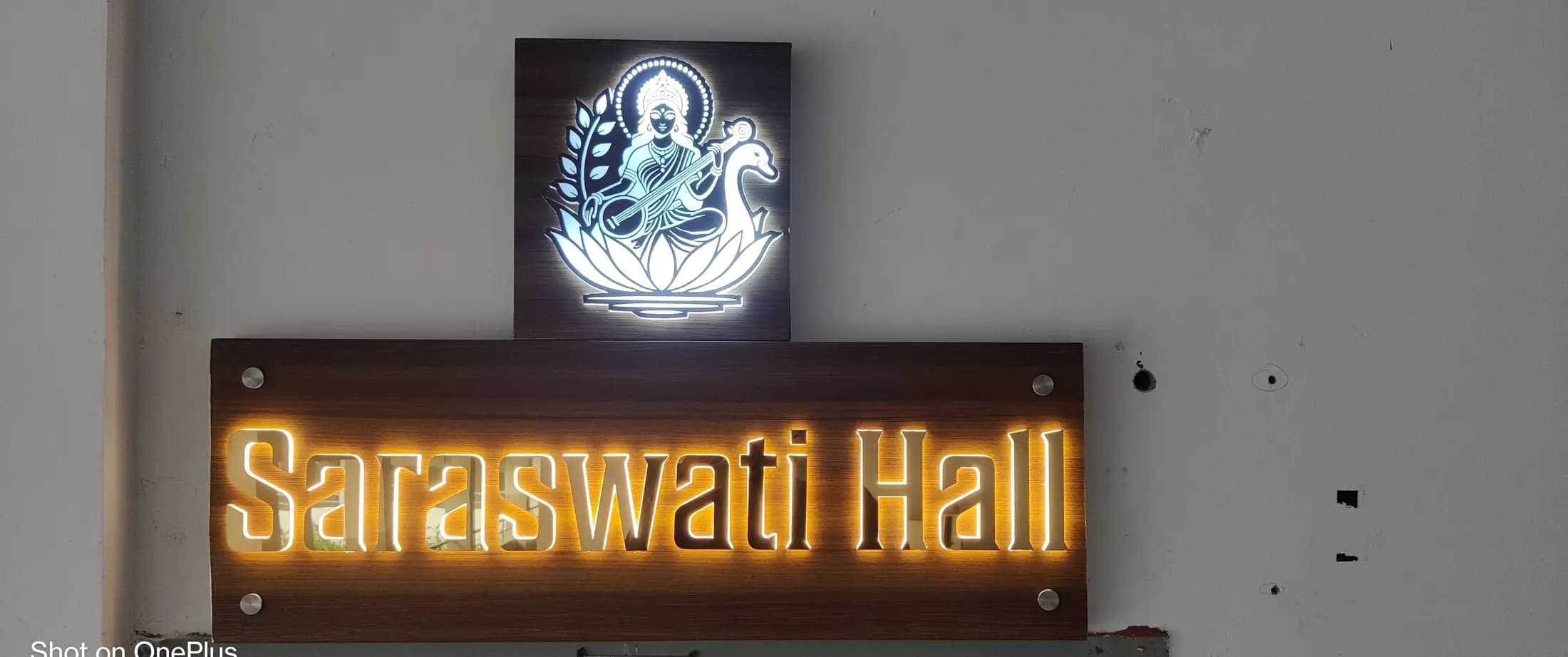 Glowing lettered sign with a backlit emblem on a white wall