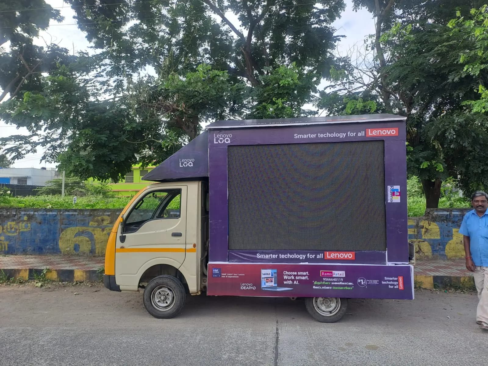 Purple-branded van carrying a large LED screen, parked on a street