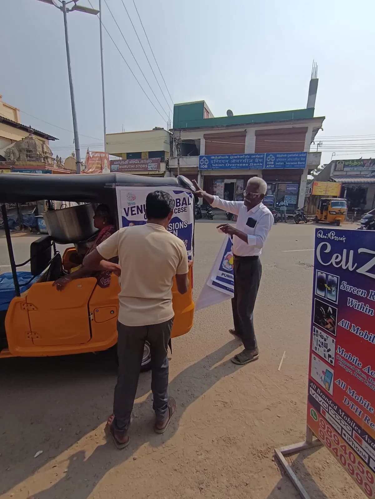Team fixing auto-rickshaw back-panel ad on street